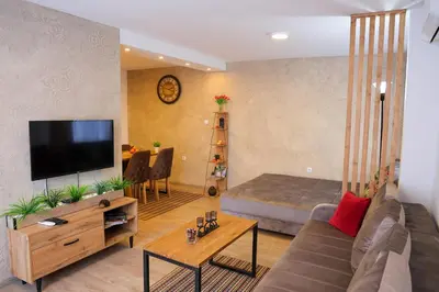 a living room with a couch and a flat screen tv at Apartman Jež in Kuršumlija