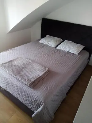 a bed with white sheets and pillows on it at Apartman Petrovic in Vrnjačka Banja