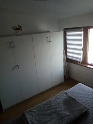 a bedroom with white cabinets and a window and a bed at Apartman Petrovic in Vrnjačka Banja