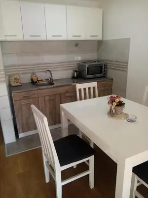 a kitchen with a white table with chairs and a microwave at Apartman Petrovic in Vrnjačka Banja