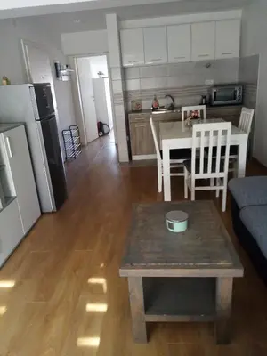 a kitchen and a living room with a table and a refrigerator at Apartman Petrovic in Vrnjačka Banja