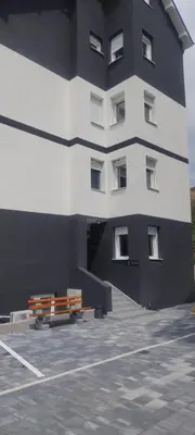 a building with a bench in a parking lot at Apartman Ivana in Soko Banja