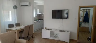 a kitchen with a table and a television on a wall at Apartman Ivana in Soko Banja