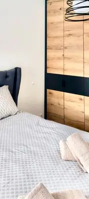 a bedroom with a white bed with a dresser at Apartman Lena in Vrnjačka Banja