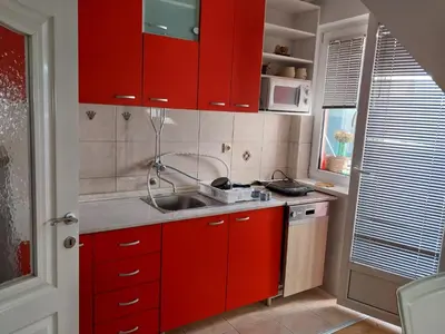 a small kitchen with red cabinets and a sink at Apartman u Nisu in Niš