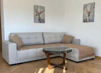 a living room with a white couch and a table at La Familia Apartmani in Vrnjačka Banja