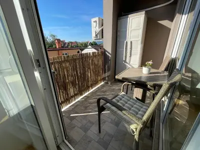 a small balcony with a table and a chair at La Familia Apartmani in Vrnjačka Banja