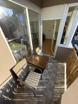 a screened in porch with a table and a chair at La Familia Apartmani in Vrnjačka Banja