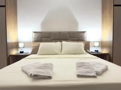 a bedroom with two towels on a bed with two lamps at Maribelle Apartments in Kruševac