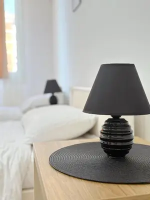 a black lamp on a table in a bedroom at Maribelle Apartments in Kruševac
