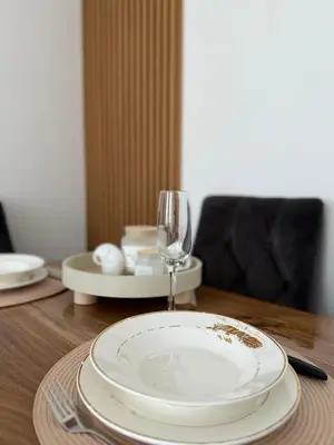 a wooden table with a plate and a wine glass at Maribelle Apartments in Kruševac