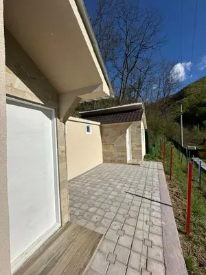 a building with a white garage door and a brick driveway at Prenociste Vranjska banja in Vranjska Banja