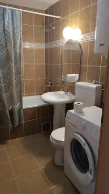 a bathroom with a toilet a sink and a washing machine at Nisava rest in Niš