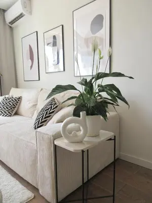 a living room with a couch with a plant on a table at Japandi Home in Niš