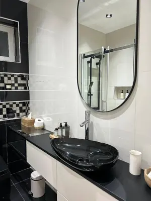 a bathroom with a black sink and a mirror at Japandi Home in Niš