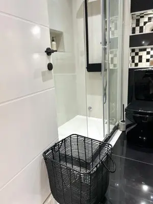 a bathroom with a glass shower and a basket at Japandi Home in Niš