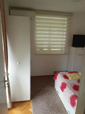 a bedroom with a bed and a window with blinds at Banjski Raj in Vrnjačka Banja