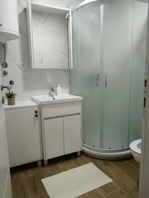 a white bathroom with a shower and a sink at Apartman Sofija in Vrnjačka Banja