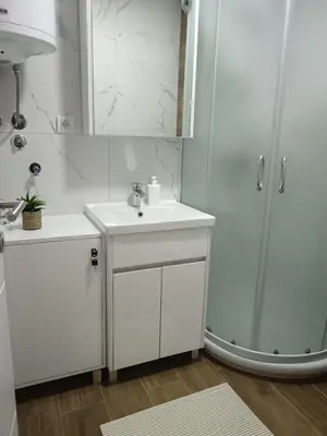 a white bathroom with a sink and a shower at Apartman Sofija in Vrnjačka Banja