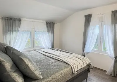 a bedroom with a bed and two windows at Villa Perla in Despotovac