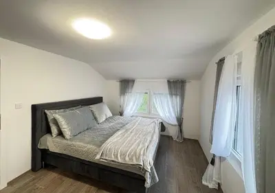 a bed in a room with white walls and windows at Villa Perla in Despotovac