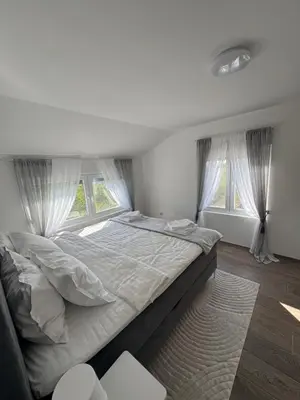 a large bed in a bedroom with two windows at Villa Perla in Despotovac