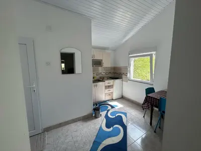 a kitchen with white walls and a table and chairs at Sobe Miloš Dimić in Sijarinska Banja
