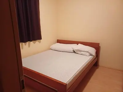 a small bedroom with a bed with white sheets at Appartement Kopaonik in Raška