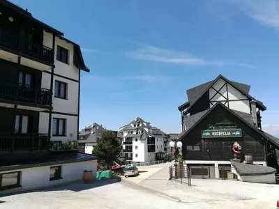 a building with a black roof in a city at Appartement Kopaonik in Raška