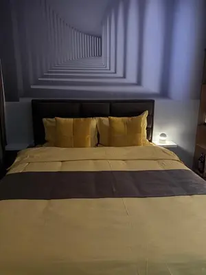 a bed with yellow pillows in a bedroom at SpaNish apartman 4 in Niš