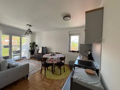 a kitchen and living room with a table and a couch at Apartman Mirka, Vrnjačka Banja in Vrnjačka Banja