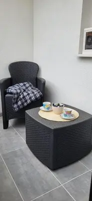 a wicker chair and a table with two bowls on it at Apartman Kety Sokobanja in Soko Banja