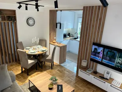 a living room with a dining room table and a television at Apartman TiHana in Pirot