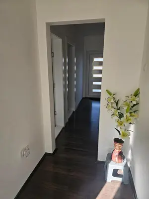a hallway with white walls and a vase on a table at Ivys apartman in Ćuprija