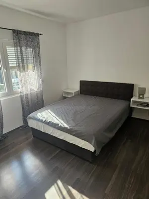 a bedroom with a large bed and a wooden floor at Ivys apartman in Ćuprija