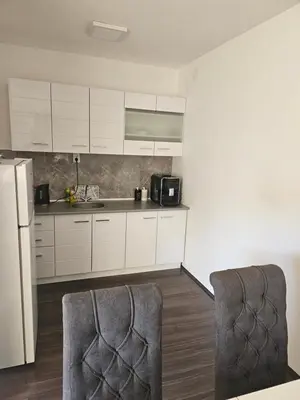 a kitchen with white cabinets and a refrigerator at Ivys apartman in Ćuprija