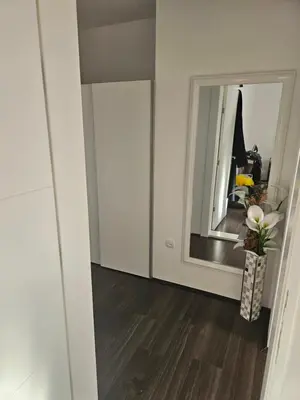 a white room with a mirror and a hallway at Ivys apartman in Ćuprija
