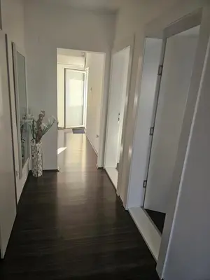 an empty hallway with white walls and wood floors at Ivys apartman in Ćuprija