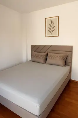 a bed in a white room with a picture on the wall at Rose casa apartments Vrnjacka Banja in Vrnjci