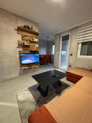 a living room with a table and a tv at Apartman ViR in Soko Banja