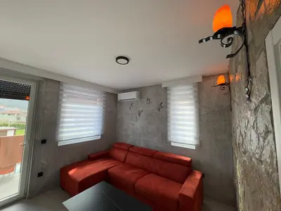 a red couch in a living room with windows at Apartman ViR in Soko Banja