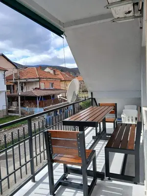 a balcony with a wooden table and chairs and a view at Vila Bela in Soko Banja