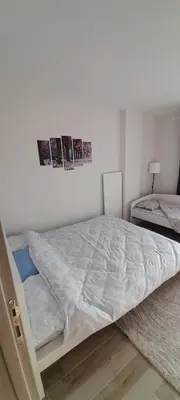 a white bed in a room with two pictures on the wall at Vila Bela in Soko Banja
