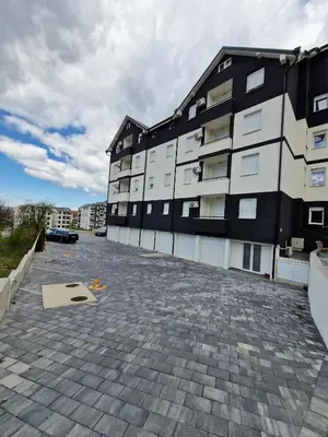 a large apartment building with a brick parking lot at Apartman Pavlović Lux in Soko Banja