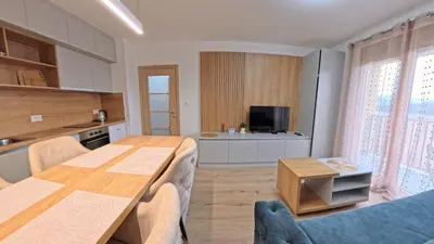 a kitchen and living room with a wooden table in a room at Apartmani Central A11 & Free parking in Vrnjci