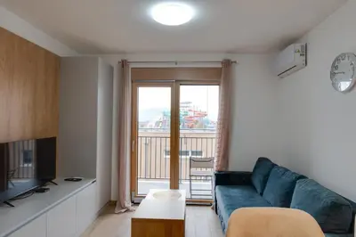 a living room with a blue couch and a balcony at Apartmani Central A11 & Free parking in Vrnjci