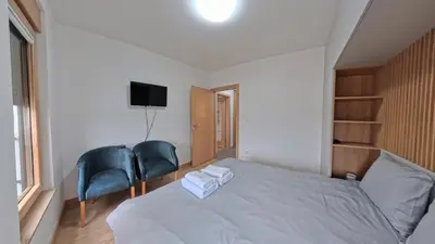 a bedroom with a bed and two chairs and a television at Apartmani Central A11 & Free parking in Vrnjci