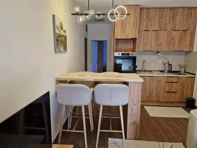 a kitchen with a counter and two stools at a kitchen island at Apartman Miha Vrnjačka Banja in Vrnjci