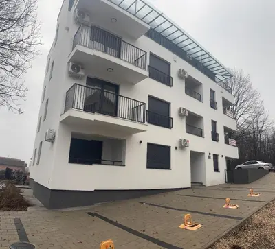 a white building with people on the ground in front of it at Apartman Miha Vrnjačka Banja in Vrnjci