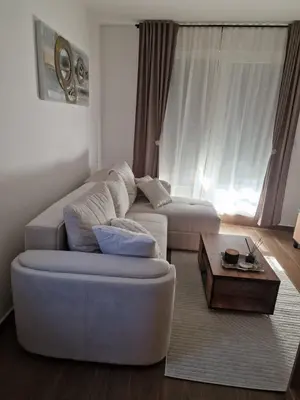 a living room with a white couch and a coffee table at Apartman Miha Vrnjačka Banja in Vrnjci